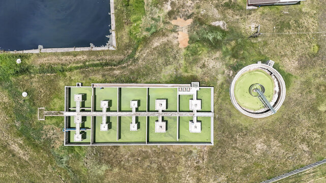 Aerial view of a water treatment facility featuring rectangular and circular tanks with green water situated near the Vaal River in Villiers, Free State, South Africa.