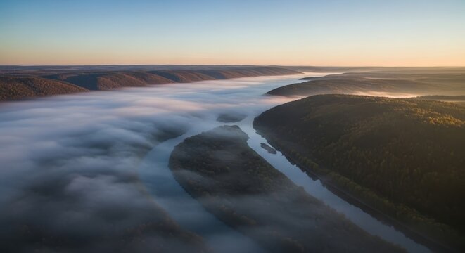 aerial view of a river flowing through a valley with fog rolling in at sunrise or sunset with a clea