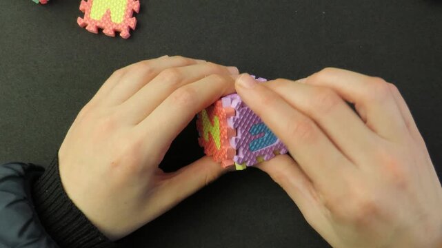 Closeup of child's hands playing with a eva foam letters puzzle. Child's hands playing with an educational toy. Kid's hands building blocks.