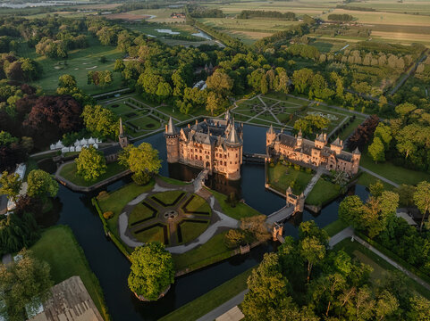 Aerial view of De Haar Castle with its towers and moat, surrounded by formal gardens and lush green forests during sunset in Utrecht, Utrecht, Netherlands.