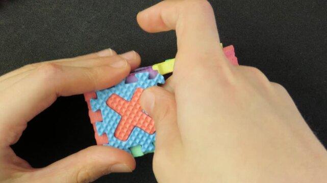 Closeup of child's hands playing with a eva foam letters puzzle. Child's hands playing with an educational toy. Kid's hands building blocks.