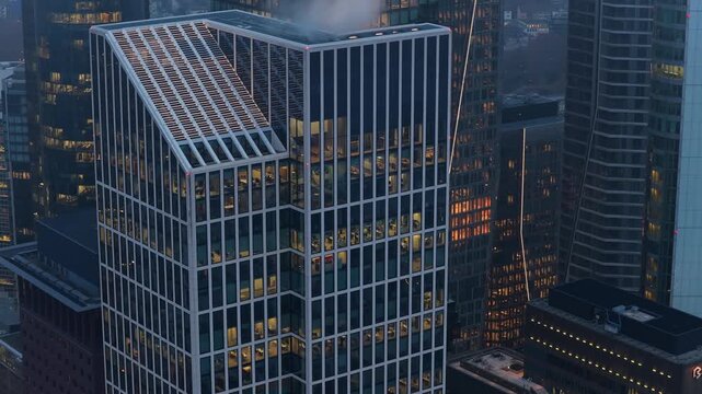 Close up aerial view of TaunusTurm modern skyscraper rooftop in Frankfurt financial district. Steam rises as lights illuminate offices