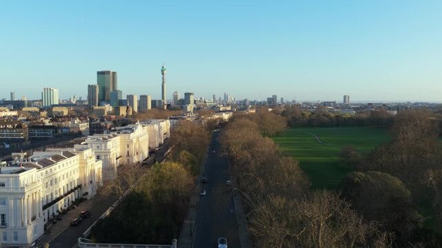 Elevated cityscape of London's Regent's Park and BT Tower, with vehicles driving along Outer Circle road and urban panorama stretching to the horizon under a clear sky