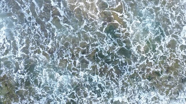 Aerial View of Ocean Waves Crashing on Rocky Shoreline
