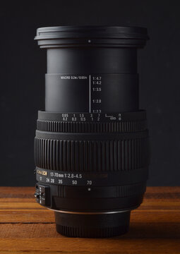 PERPIGNAN, FRANCE - MAY 5, 2026: A Sigma 17-70mm 2.8-4.5 DC Macro lens for digital SLR cameras, placed on a wooden surface. This versatile zoom lens was a popular high-performance alternative to stand