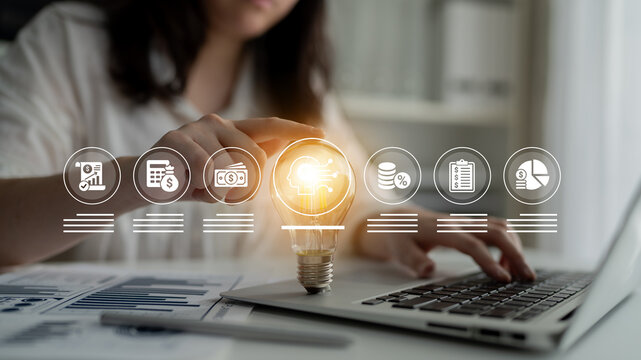 A person interacts with a laptop in a modern workspace, showcasing business innovation through a light bulb, highlighting financial analysis and digital marketing concepts effortlessly. Ledger