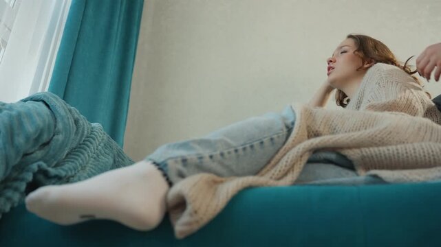 Relaxed Girl Laughing, Caucasian Woman Relaxing On Couch As Friend Styles Her Hair, Young Woman With Light Skin Lounging On Sofa While Friend Playfully Adjusts Her Hair In Cozy Living Space