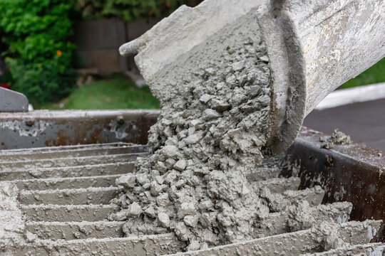 Wet concrete pouring from chute into mixer, close up of fresh cement mixture with gravel, construction process, building materials, industrial work detail