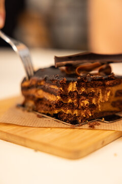 close up depth of field of fork cutting into rich decadent layered chocolate cake in a restaurant