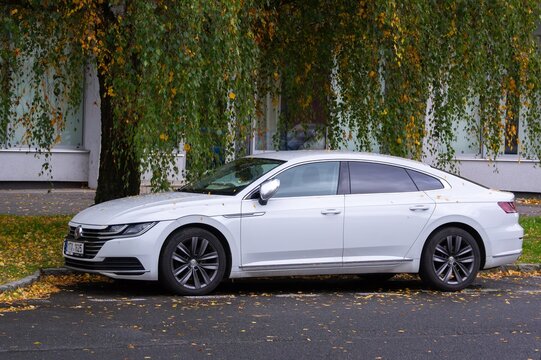 White Volkswagen Arteon luxury sedan parked on street in autumn