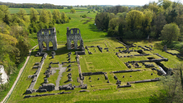 Aerial view of the historic stone ruins of Roche Abbey with its Gothic arches and foundations surrounded by lush green lawns and dense woodland in Maltby, England, United Kingdom.