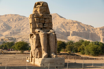 Colossi of Memnon stands tall in the Valley of the Kings under the sun in Luxor, Egypt during the early morning hours © denklim
