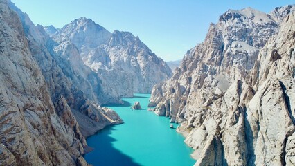 Obraz premium Aerial drone view of Köl-Suu Lake in At-Bashy District, showing turquoise waters surrounded by rugged alpine mountains.