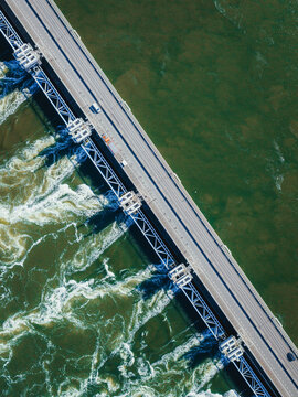 Aerial view of the Eastern Scheldt Storm Surge Barrier with rushing water through the gates and a car on the road in Vrouwenpolder, Zeeland, Netherlands.
