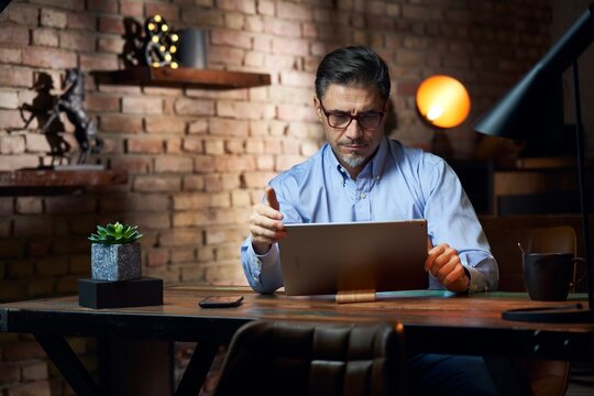 Man working from home in home office with tablet computer at desk in trendy room.