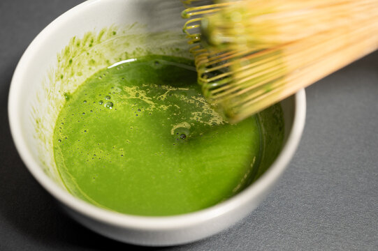Preparing matcha green tea with traditional bamboo whisk