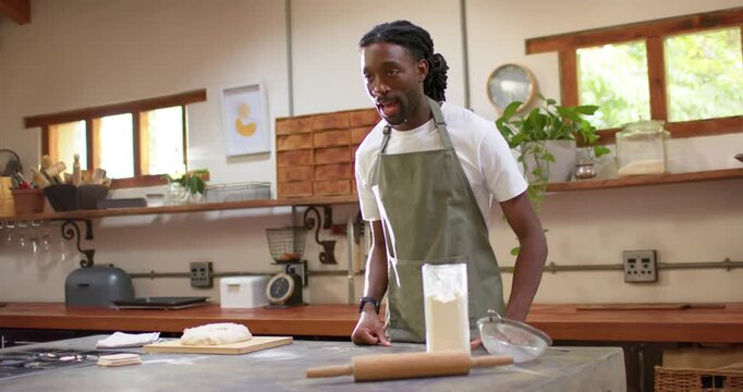 African American man speaking, showing recipe steps and smoothing dough on cutting board