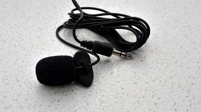 Close-up of lavalier microphone on smooth surface, ready to capture audio with elegance and precision.