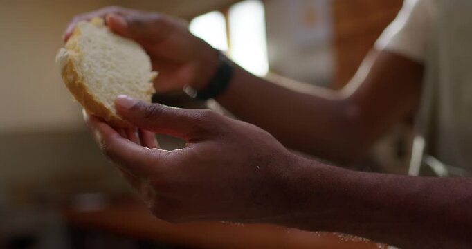 African American man inspecting bread, steam rising, tearing crumb and testing softness in kitchen