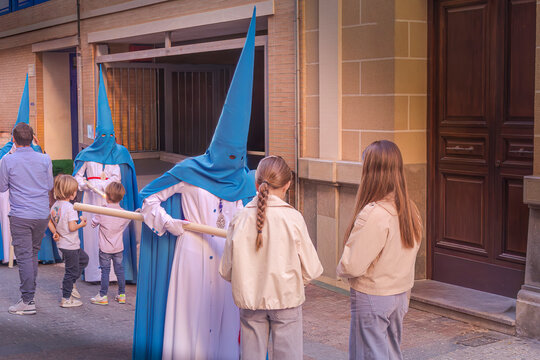 penitentes de una hermandad dandole cera de los cirios a ni&ntilde;os para hacer bolas de cera, Huelva, Espa&ntilde;a