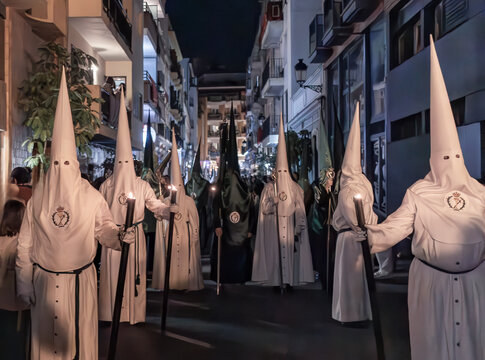 penitentes de una hermandad con grandes cirios de procesi&oacute;n de Semana Santa en huelva, Espa&ntilde;a