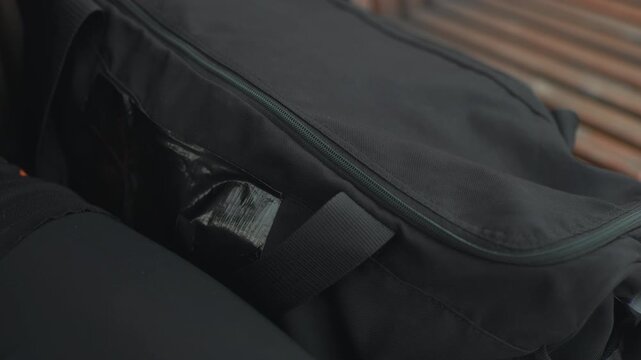 Preparing equipment for workout, Focused individual organizing training supplies diligently, An individual with tattooed arms carefully zips up their athletic bag filled with training essentials