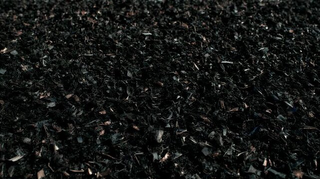 Close-up of shredded recycled material. Dark rubber mulch or compost for sustainable landscaping. Industrial waste processing and resource recovery concept