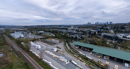Obraz premium Aerial View Of Industrial Yard And Burnaby City Skyline Over Greater Vancouver, British Columbia, Canada