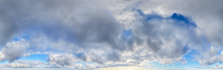 Obraz premium Dramatic Cloudscape Over Blue Sky With Moody Cumulus Clouds and Low Horizon Panorama