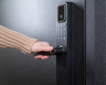 A woman opens a modern smart door lock with a digital keypad and biometric fingerprint access.