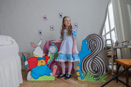 Smiling White Girl With Colorful Props And Cardboard Characters, Lively Studio Scene Capturing Playful Energy, Longhair Curls, Cheerful Expression, Partyready Costume And Oversized Playing Cards