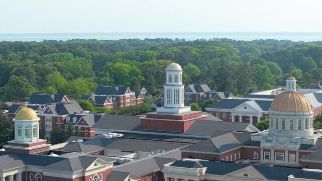 Christopher Newport University campus, a sweeping aerial drone view showcasing the grand neoclassical brick architecture, iconic golden domes, and manicured green lawns of the CNU campus in Newport Ne