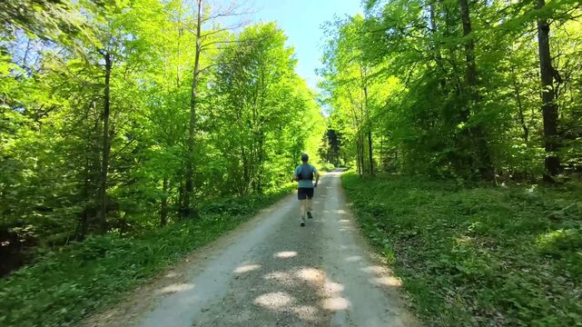 Trail runner filmed from behind moving through Swiss forests, immersed in nature and silence, experiencing freedom, mental clarity and balance, escaping digital noise and reconnecting with self.