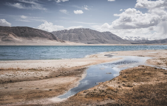 Mountain landscape, a cold high-altitude lake against the backdrop of rocky peaks and ridges with snow and glaciers, a panorama in the Tien Shan Mountains in the Pamirs, a lake with waves