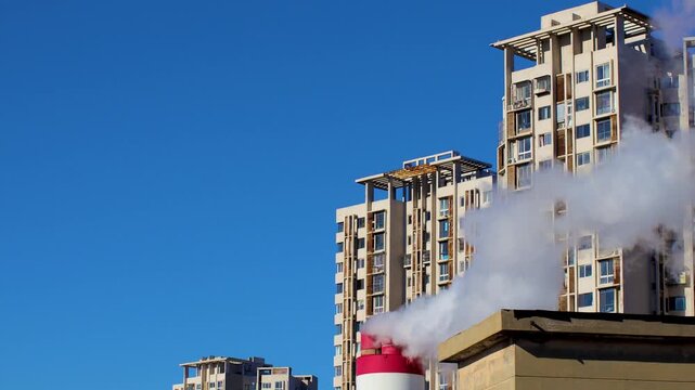 Industrial chimney smoke near modern apartment buildings