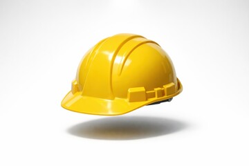 Fototapeta premium A yellow hard hat is suspended above a light background. This scene highlights the importance of safety in construction settings.