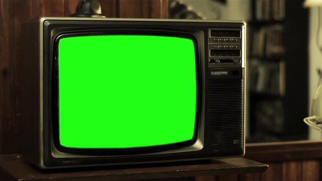 Man Dialing A Vintage Rotary Phone Next To A Green Screen Television - 4K