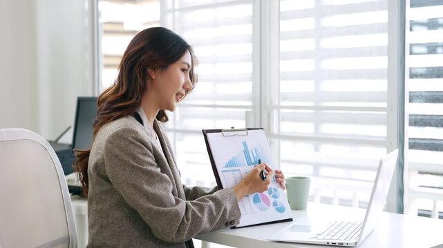 Business woman talking on a video call in office. Business woman having an online meeting with team. Professional business woman doing remote work.