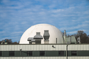 Fototapeta premium White industrial dome behind green factory roof and rooftop ventilation units.