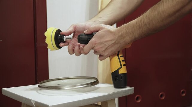 Caucasian man unscrewing chuck of screwdriver to replace and install foam polishing attachment closeup. Process of changing attachment in cordless drill with keyless chuck.
