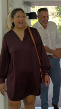Vertical video: Arriving couple shaking hands with agent while touring entry hall holding portfolio