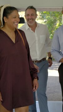 Vertical video: Opening front door, host meeting couple, shaking hands and showing foyer with folio