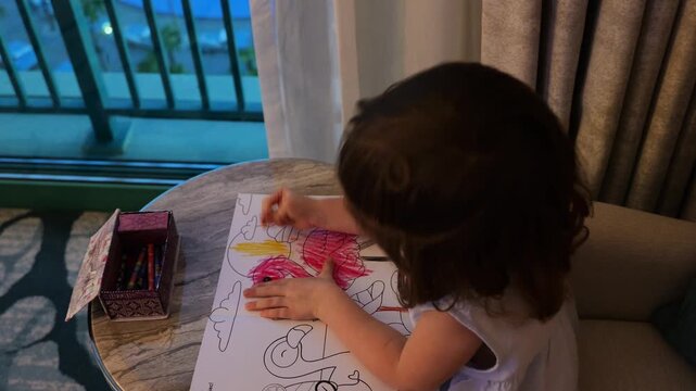 Little girl drawing with crayons in a hotel room