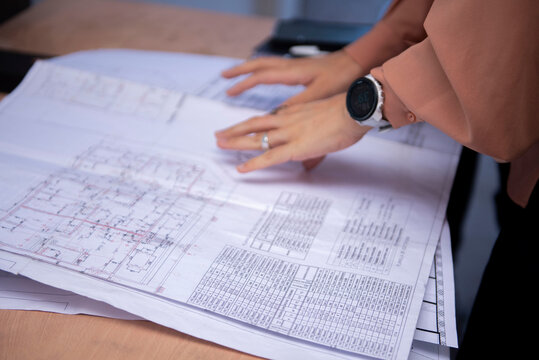 Architect discussing building plan blueprint with smartphone on desk