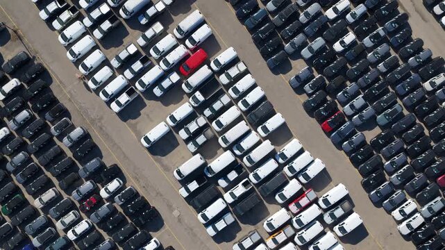 Vast parking lot filled with hundreds of brand new vehicles parked in diagonal rows, showcasing the scale of modern automotive production, logistics, and international vehicle distribution