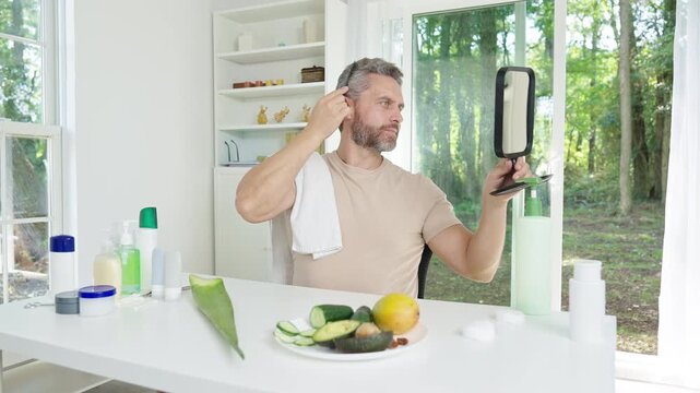 Healthy grooming habit of combing hair daily. Man combing hair as part of wellness routine. Male hairstyle preparation by combing hair. Clean and neat look achieved by combing hair.