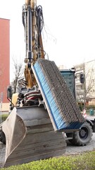 Specjalistyczna koparka kołowa wyposażona w profesjonalną frezarkę do asfaltu podczas precyzyjnych prac remontowych na miejskim chodniku, zapewniająca wysoką wydajność i dokładność w trudnym terenie © tomo81