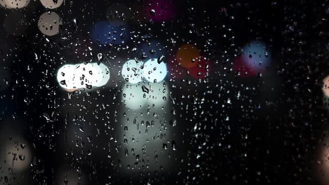 Rainy Night City Lights Bokeh. Abstract Urban Background with Raindrops. 
Blurred night city lights with soft bokeh effect and falling rain create a calm, cinematic urban atmosphere.