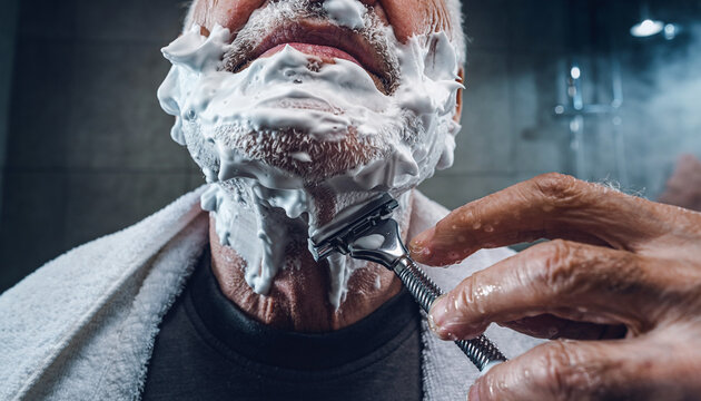 Man shaving with foam in bathroom with a worm's eye view showing his chin and razor during morning routine