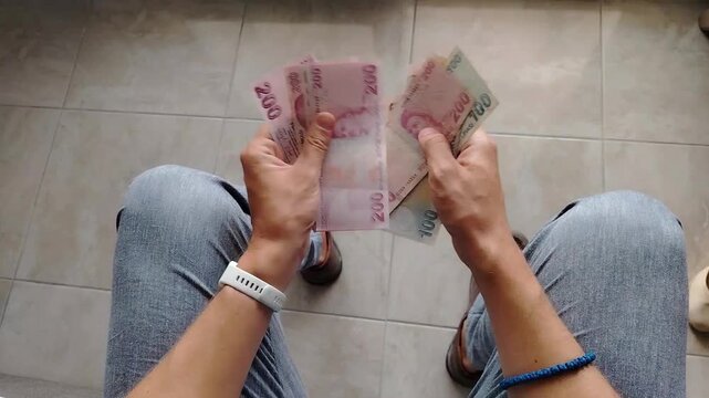 Man counting Turkish lira mixed banknotes at home, personal finance concept, cash handling, budgeting activity, savings and spending control.
